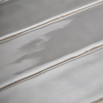 Os ladrilhos cerâmicos retangulares ficam horizontalmente, apresentando uma superfície brilhante e ondulada com sulcos sutis e u