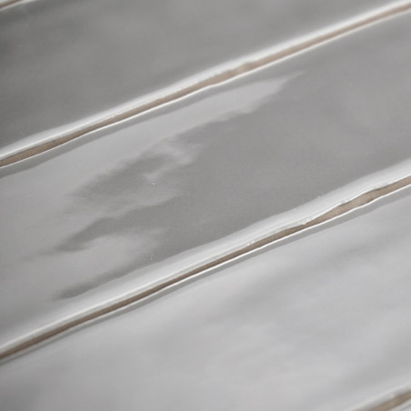 Les carreaux de céramique rectangulaires sont posés horizontalement, présentant une surface brillante et ondulée avec des crêtes