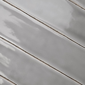 Ladrilhos cinza lisos e brilhantes são alinhados diagonalmente. A superfície reflete a luz, mostrando padrões sutis semelhantes 