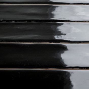 Glänzend schwarze rechteckige Fliesen liegen in parallelen Reihen und spiegeln den wolkigen Himmel darüber wider, wodurch ein el