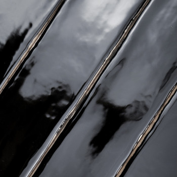 Les carreaux noirs brillants reflètent la lumière, créant un effet miroir ondulé. La surface apparaît humide, mettant en valeur 