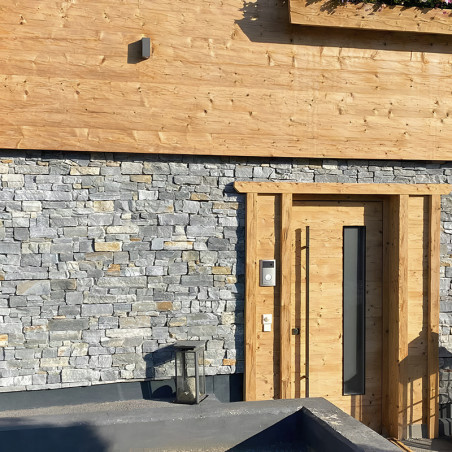 Muro de pedra em meio a um quintal, cercado por grama exuberante e árvores, adjacente a um canto de edifício moderno. Muro de pedra em meio a um quintal, cercado por grama exuberante e árvores, adjacente a um canto de edifício moderno.