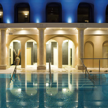 Zwembad reflecterende bogen en kolommen. warme lichten verlichten de gevel van het gebouw in een serene, overdekte spa-omgeving.