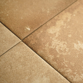 Quatre carreaux carrés texturés se croisent, présentant des tons brun terreux et des variations subtiles. Ils forment un quadril