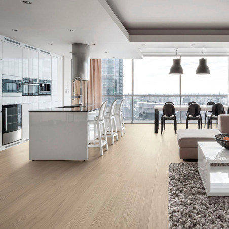 Una amplia y moderna cocina-comedor cuenta con elegantes gabinetes blancos y una isla, rodeada de taburetes, un lujoso sofá y vi
