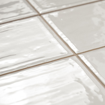 Les carreaux de céramique blanche présentent une surface brillante avec des textures légèrement ondulées, disposées selon un mot