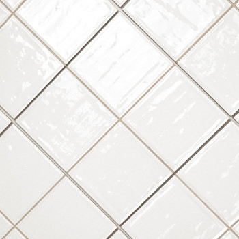 Witte keramische tegels diagonaal gerangschikt met een glanzende afwerking. de voegenlijnen vormen een contrasterend rasterpatro