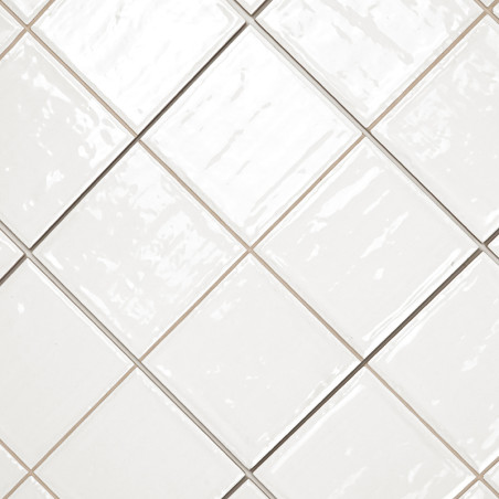 Carreaux de céramique blanche disposés en diagonale avec une finition brillante. les lignes de coulis forment un motif de grille Carreaux de céramique blanche disposés en diagonale avec une finition brillante. les lignes de coulis forment un motif de grille