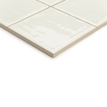 Een beige keramische tegel met een glanzende afwerking, gesegmenteerd in vier kleinere vierkanten, verschijnt tegen een effen wi