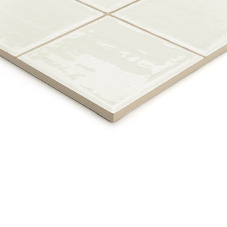 Een beige keramische tegel met een glanzende afwerking, gesegmenteerd in vier kleinere vierkanten, verschijnt tegen een effen wi