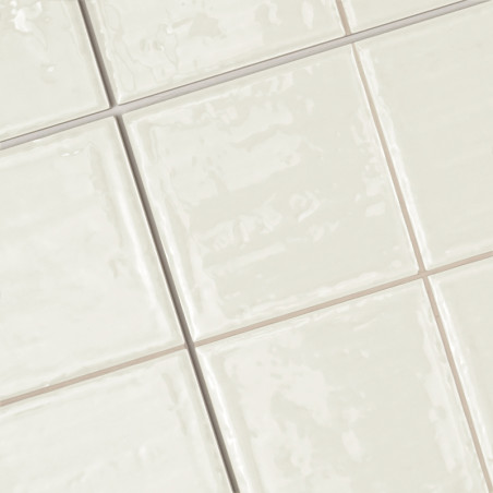 Keramische tegels, gerangschikt in een rasterpatroon, vertonen een glanzend, lichtbeige oppervlak. Ze creëren een strak, gepolij