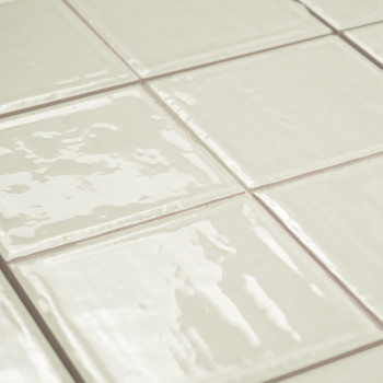 Glanzende, gebroken witte vierkante tegels gerangschikt in een rasterpatroon. ze reflecteren licht, waardoor een strak oppervlak