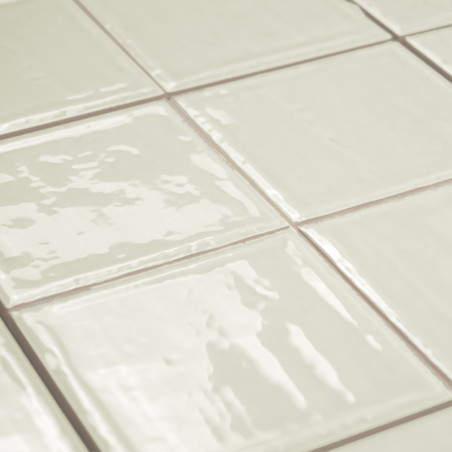 Glanzende, gebroken witte vierkante tegels gerangschikt in een rasterpatroon. ze reflecteren licht, waardoor een strak oppervlak