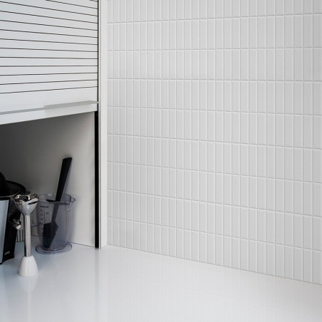 Los azulejos verticales blancos del metro cubren una pared y reflejan la luz en una cocina elegante y moderna con gabinetes y un