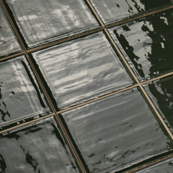 Las brillantes azulejos de cerámica de color verde oscuro reflejan la luz, dispuestas en una ordenada cuadrícula con líneas de l