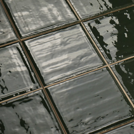 Shiny, dark green ceramic tiles reflect light, arranged in a neat grid with visible grout lines, creating a glossy, textured sur