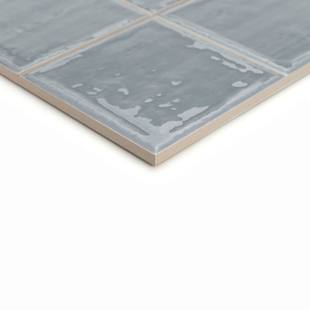 Les carreaux de céramique gris présentent une finition brillante et un motif légèrement irrégulier. Les tuiles sont disposées da