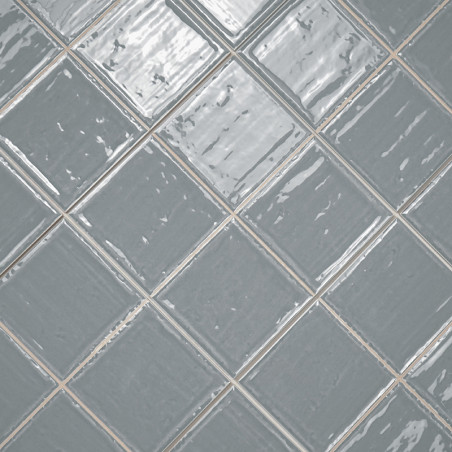 Les carreaux de céramique gris disposés selon un motif de grille diagonale, réfléchissant la lumière, créent un aspect brillant 