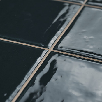 Les carreaux bleu foncé brillants sont alignés selon un motif en grille, réfléchissant la lumière de manière légèrement déformée