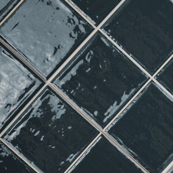Carreaux de céramique alignés en diagonale. La surface noire brillante et réfléchissante crée un aspect texturé et ondulé. dispo