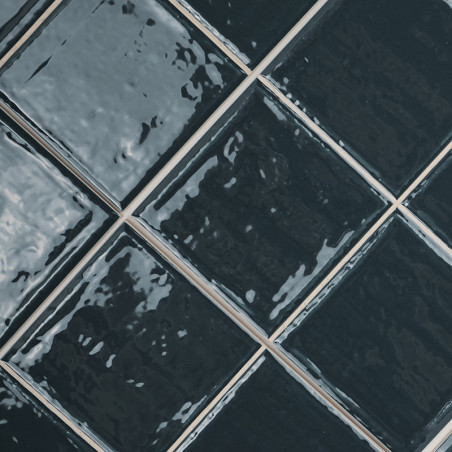 Carreaux de céramique alignés en diagonale. La surface noire brillante et réfléchissante crée un aspect texturé et ondulé. dispo