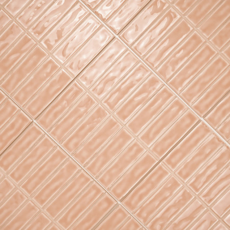 Rechthoekige perzikkleurige tegels zijn diagonaal gerangschikt, waardoor een golvend reflecterend patroon ontstaat over een vlak