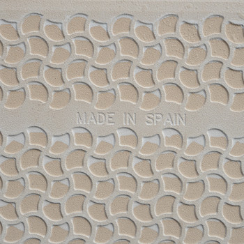 Een beige tegel vertoont een verhoogd, halfrond patroon in een herhalend geometrisch ontwerp. De centrale tekst luidt: `MADE IN 