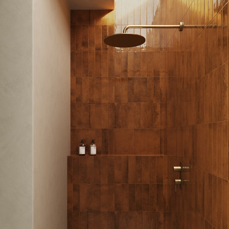 Een bronzen douchekop steekt uit een betegelde muur en verdrijft denkbeeldig water in een moderne badkamer met amberkleurige teg