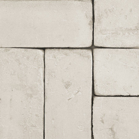 Rechthoekige terracottategels liggen plat en vormen een in elkaar grijpend patroon. Eromheen bindt een gladde, neutraal getinte 