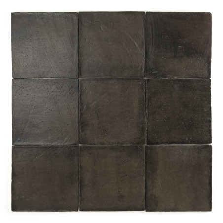 Neuf carreaux de terre cuite noire sont soigneusement disposés selon un motif de grille carrée sur un fond blanc.