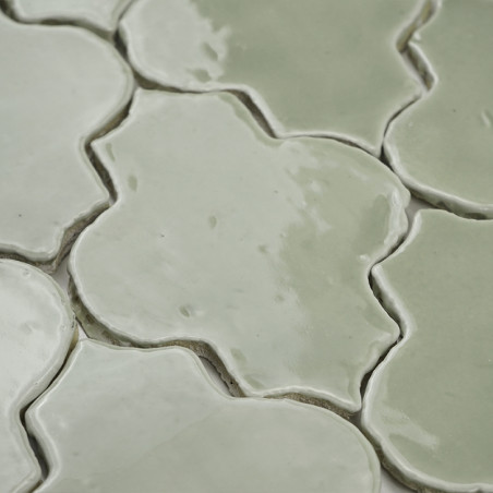 Interlocking green terracotta tiles form a patterned surface, highlighting their glossy finish and soft color variation.