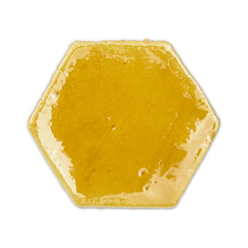 Ladrilhos hexagonais de terracota amarela formam uma parede texturizada acima de uma mesa de madeira com velas e itens decorativ