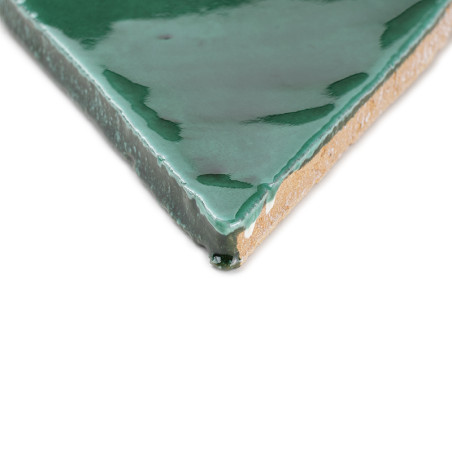 Una losa de terracota vidriada en verde descansa sobre un fondo blanco, resaltando su acabado brillante y su parte inferior de a