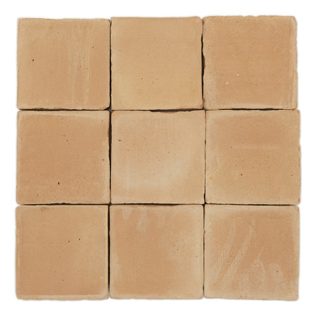 Carreaux carrés en terre cuite soigneusement disposés, mettant en valeur des tons terreux et des textures lisses, sur un fond bl