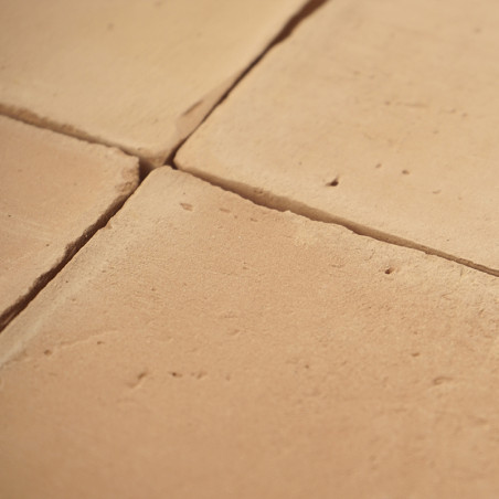 Os ladrilhos de terracota são dispostos em grade, formando uma superfície rústica em tons quentes sob luz natural.