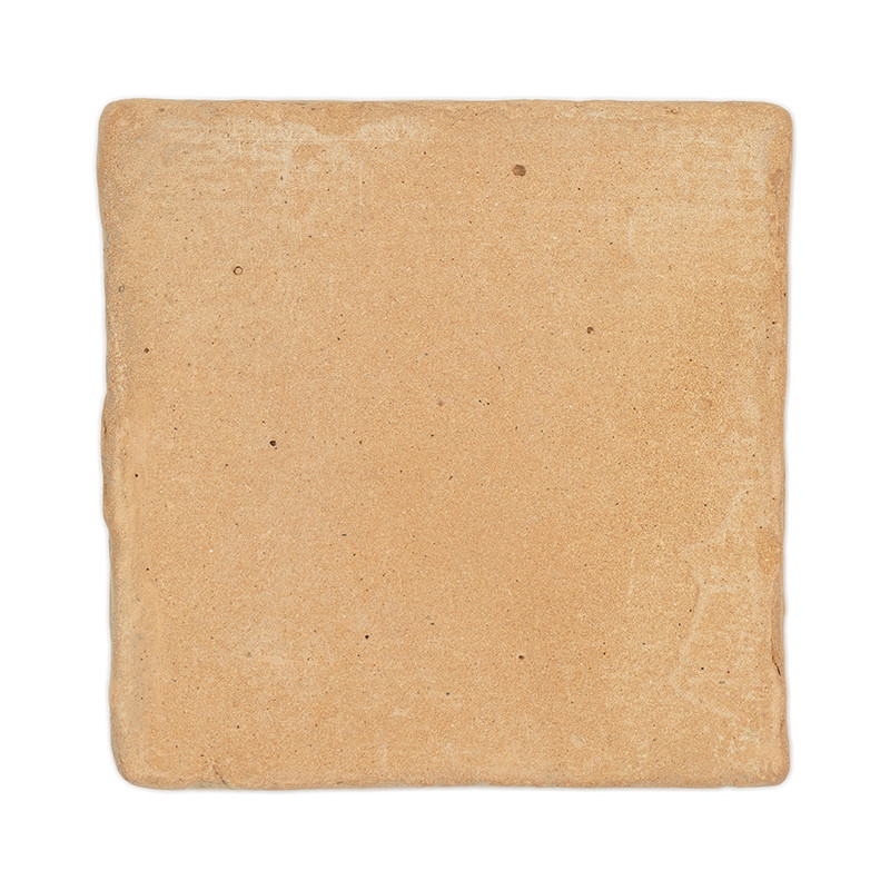 Un carreau carré en terre cuite repose sur un fond blanc, montrant une surface rugueuse et texturée avec des imperfections natur