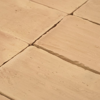 Os ladrilhos de terracota são dispostos em padrão de espinha de peixe, criando um piso rústico em um ambiente interno aconchegan
