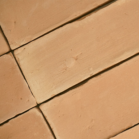 Terracotta tiles lie flat, forming a geometric pattern, with a slightly rough texture and a warm, earthy tone.