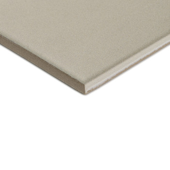 Un azulejo cerámico cuadrada de color gris con una superficie lisa yace sobre un fondo blanco, mostrando su espesor con un borde