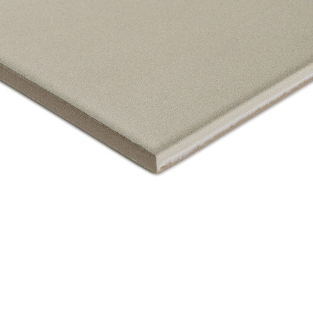 Un carreau de céramique carré gris à surface lisse repose sur un fond blanc, montrant son épaisseur avec un bord visible.