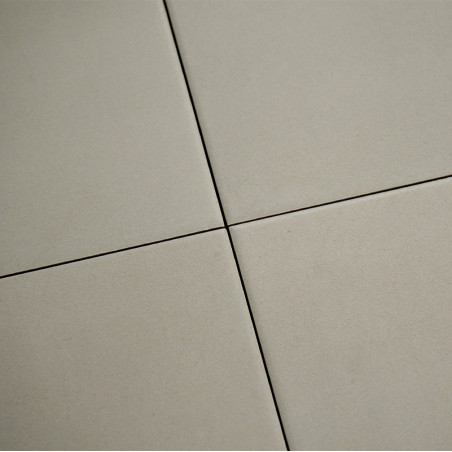 Quatre carreaux beiges se rencontrent avec des lignes de coulis étroites et sombres formant un motif en croix. la surface appara