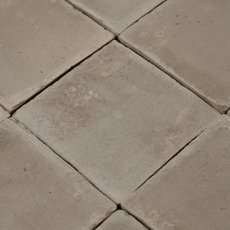 Azulejos cuadradas de terracota lisas dispuestas en forma de cuadrícula, formando una superficie de tonos neutros en un ambiente