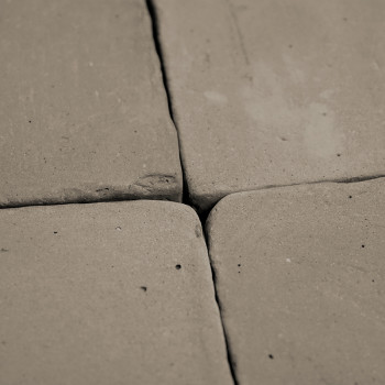 Four terracotta tiles, placed closely, form a square pattern. surface displays uneven, rustic texture and subtle imperfections.