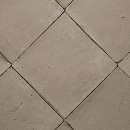 Carreaux de terre cuite disposés en diagonale, créant un motif en losange sur un sol plat de couleur neutre.