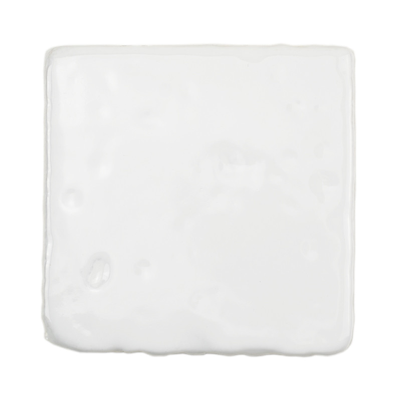 Un azulejo de terracota blanco liso y brillante se encuentra aislado sobre un fondo liso y sin rasgos distintivos.