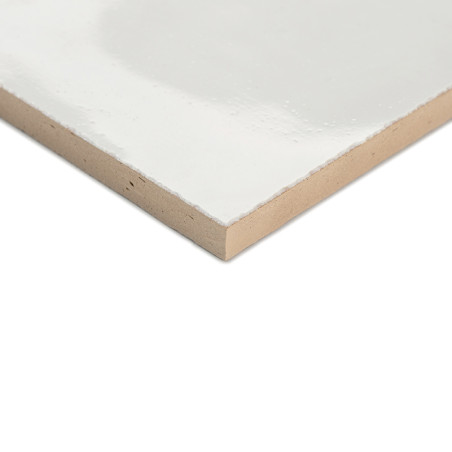 Een gladde, wit geglazuurde terracotta tegel ligt plat en laat het glanzende oppervlak en de beige randen zien tegen een effen a Een gladde, wit geglazuurde terracotta tegel ligt plat en laat het glanzende oppervlak en de beige randen zien tegen een effen a