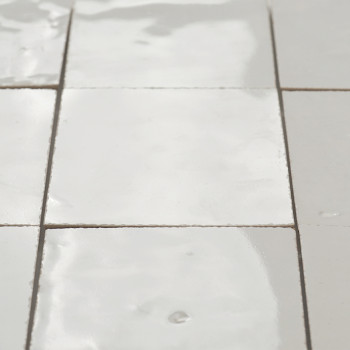 Les carreaux de terre cuite brillantes sont disposés de manière transparente, avec de légères imperfections, reflétant la lumièr