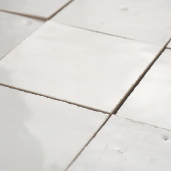 Square terracotta tiles are laid out in a grid pattern, their surfaces smooth and glossy, reflecting soft light.