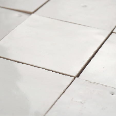 Vierkante terracottategels zijn in een rasterpatroon gelegd, hun oppervlakken zijn glad en glanzend en reflecteren zacht licht. Vierkante terracottategels zijn in een rasterpatroon gelegd, hun oppervlakken zijn glad en glanzend en reflecteren zacht licht.