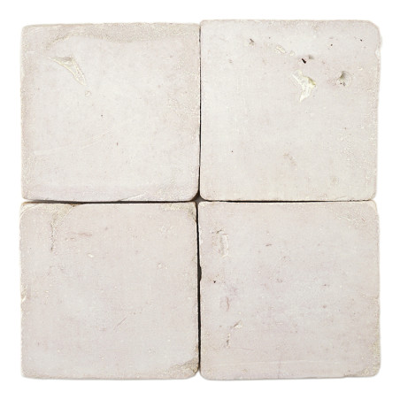 Quatre carreaux carrés en terre cuite posés ensemble, affichant de subtiles variations de texture, sur un fond blanc uni.